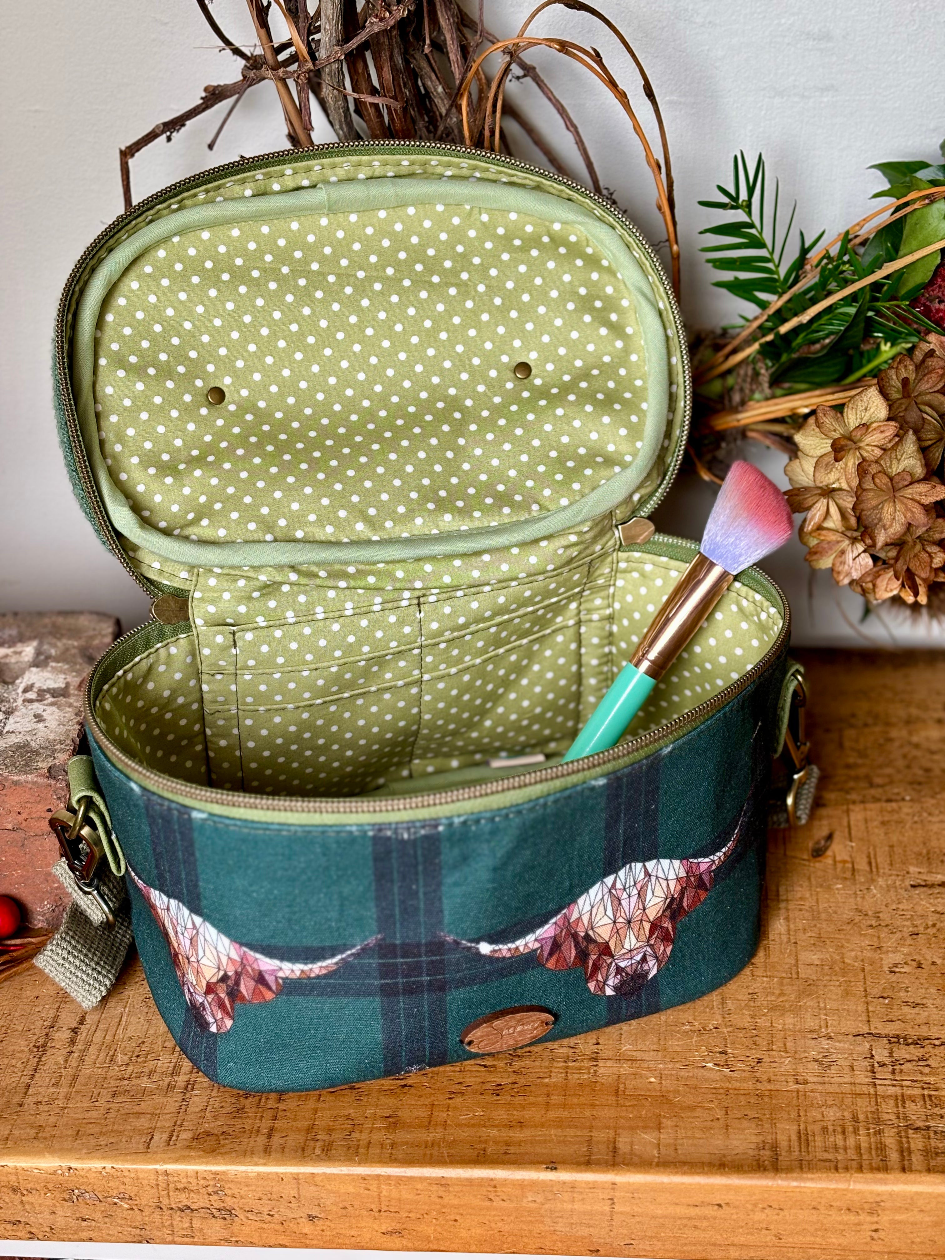 Charming Highland Cows Teresita Train Case, showcasing adorable Highland cattle in a picturesque design in green hues, providing both functionality with a green polka dot lining.